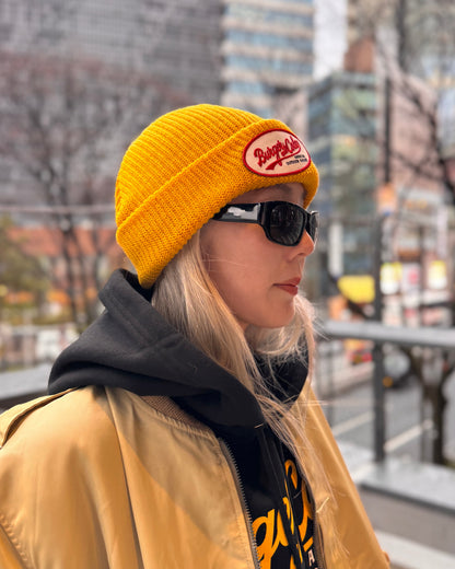 BURGER&COLA B&C OVAL Patch Beanie（ビーニー）マスタード色のワッペンのアップ（横向き、着用）