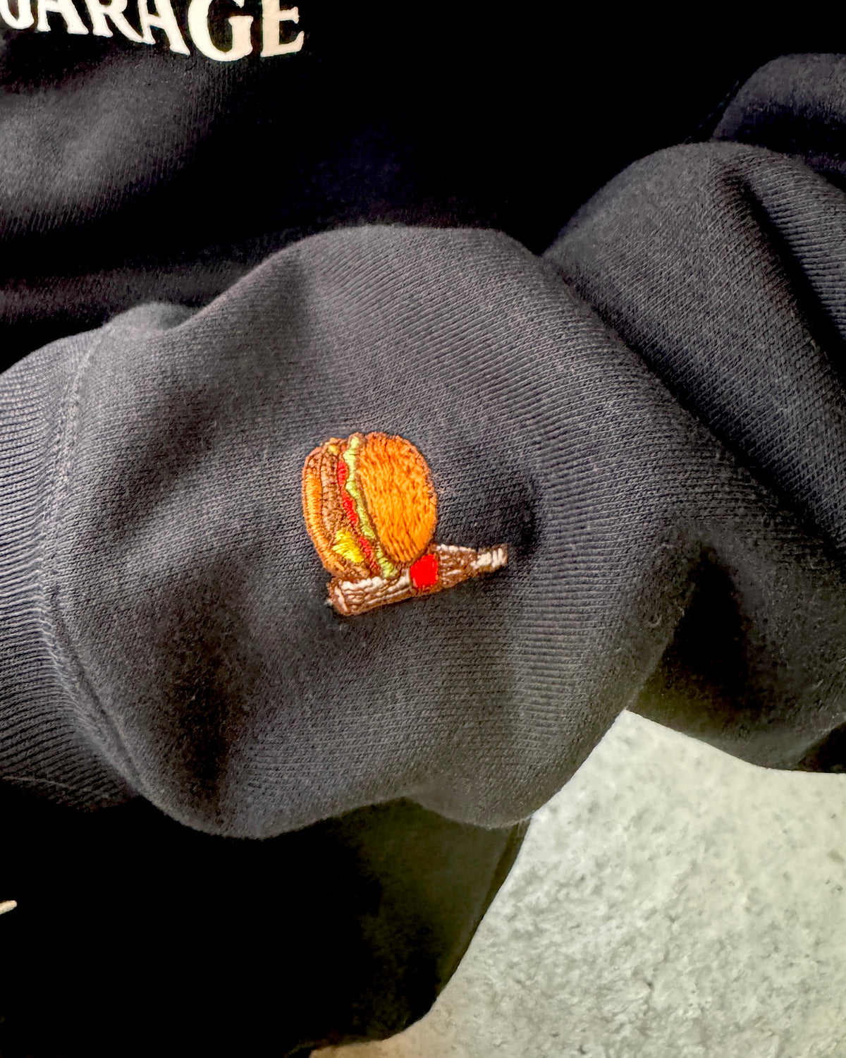 BURGER&COLA B&C FRONT LOGO HOODIE BLK（パーカー）袖の刺繍ロゴのアップ